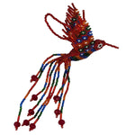 A handmade beaded hummingbird ornament featuring a red, orange, blue, and green wings with white dots, and a tail of the same colors and red faceted glass crystal beads, against a plain white background.
