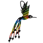 A handmade beaded hummingbird ornament featuring a vibrant rainbow gradient on its body and wings, with long trailing beaded tails with black crystals and a black beaded head, set against a plain white background.