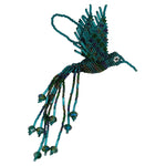 A handmade beaded hummingbird ornament in shades of green, featuring long trailing bead strands set against a plain white
background.