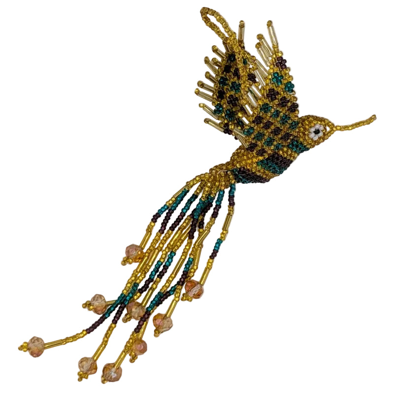 A handmade beaded hummingbird ornament, featuring seed beads in gold, teal, and grape, with dangling clear gold faceted beads at the tail, shown on a plain white background.