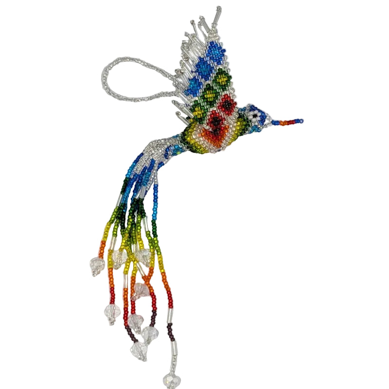 A handmade beaded hummingbird ornament with a vibrant multicolor design, featuring a silver wire loop at the top for hanging. The body and wings are crafted with blue, green, yellow, red, and orange beads, adorned with dangling clear crystal beads, set against a plain white background.