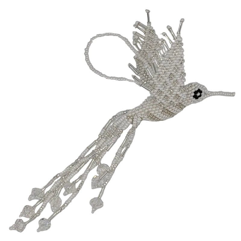 A handmade beaded hummingbird ornament, crafted with white and silver-toned seed beads, featuring a small black eye detail and a hanging loop at the top, set against a plain white background.