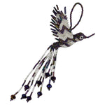 A handcrafted beaded hummingbird ornament, made from white and iridescent purple seed beads, photographed on a plain white background.