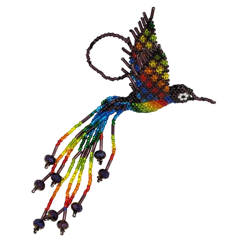 A colorful beaded hummingbird ornament on a plain white background. The bird features a vibrant rainbow gradient on its body and wings, burgundy-purple seed bead details, and long trailing beaded tails with rainbow color beads.