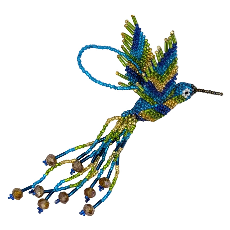 A handmade beaded hummingbird ornament, featuring vibrant blue, green, and gold seed beads with dangling bead strands and faceted bronze beads, set against a plain white background.