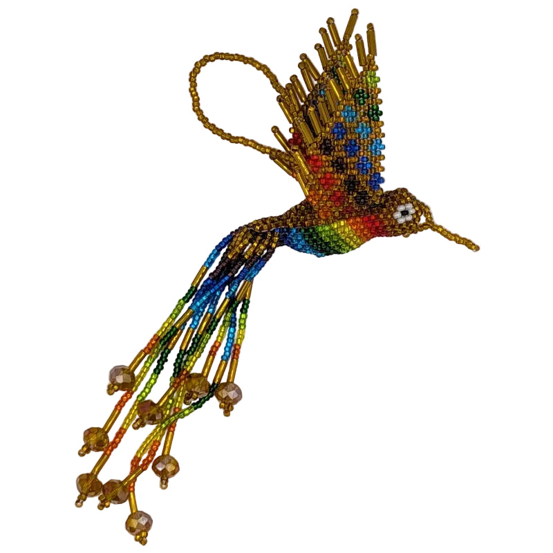 A handmade beaded hummingbird ornament featuring a vibrant rainbow pattern in dark gold on its body and wings, with long trailing rainbow beaded tail feathers and a gold-tone hanging loop, shown on a plain white background.