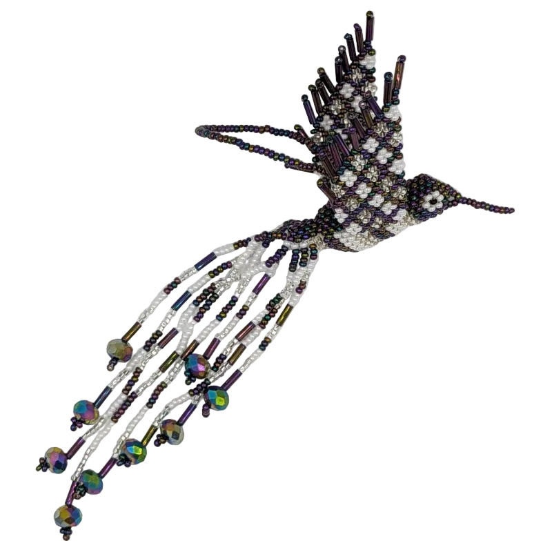 A handcrafted beaded hummingbird ornament made from white seed beads, dark purple beads, and iridescent faceted beads, photographed on a white background.